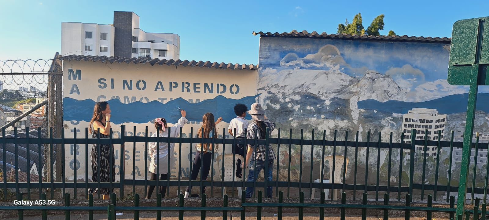 Profesora de arte Diana Carolina Ortíz con 4 estudiantes renovando uno de los mural es