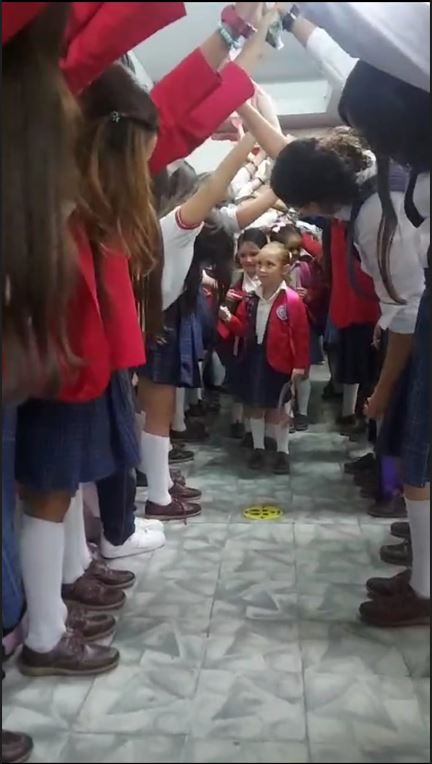 Calle de honor que estudiantes de secundaria hacen a alumnas de primaria